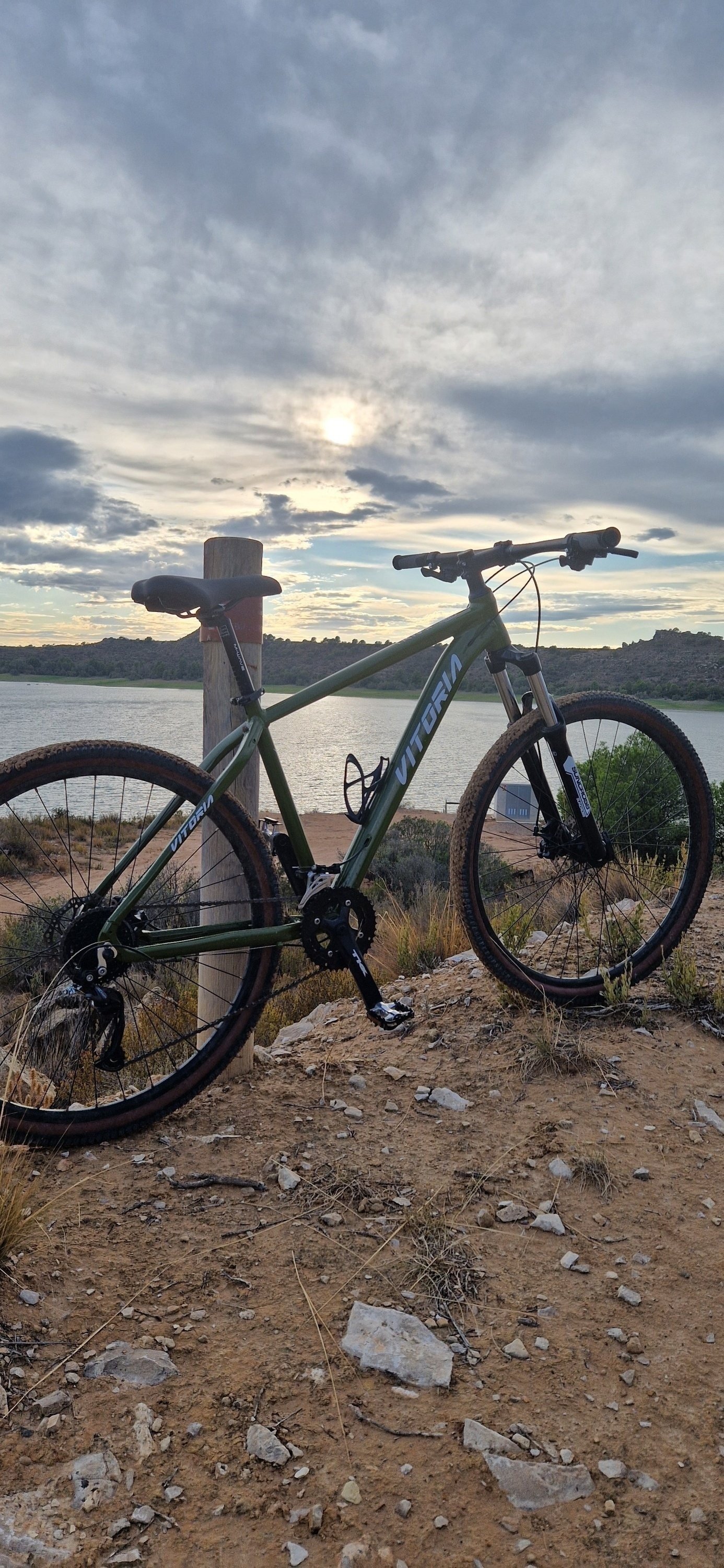 un vélo vert vitoria est garé sur un rocher près d' un lac