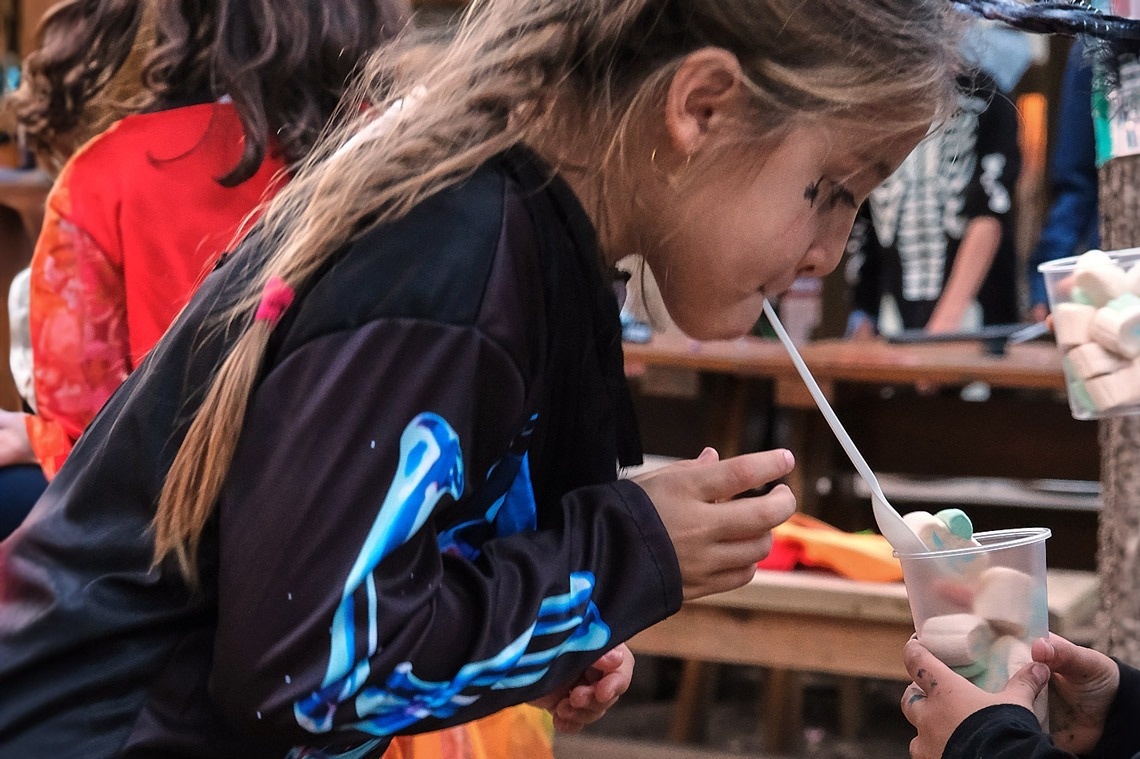 una jove disfressada de bruixa beu marshmallows a través d' un llop