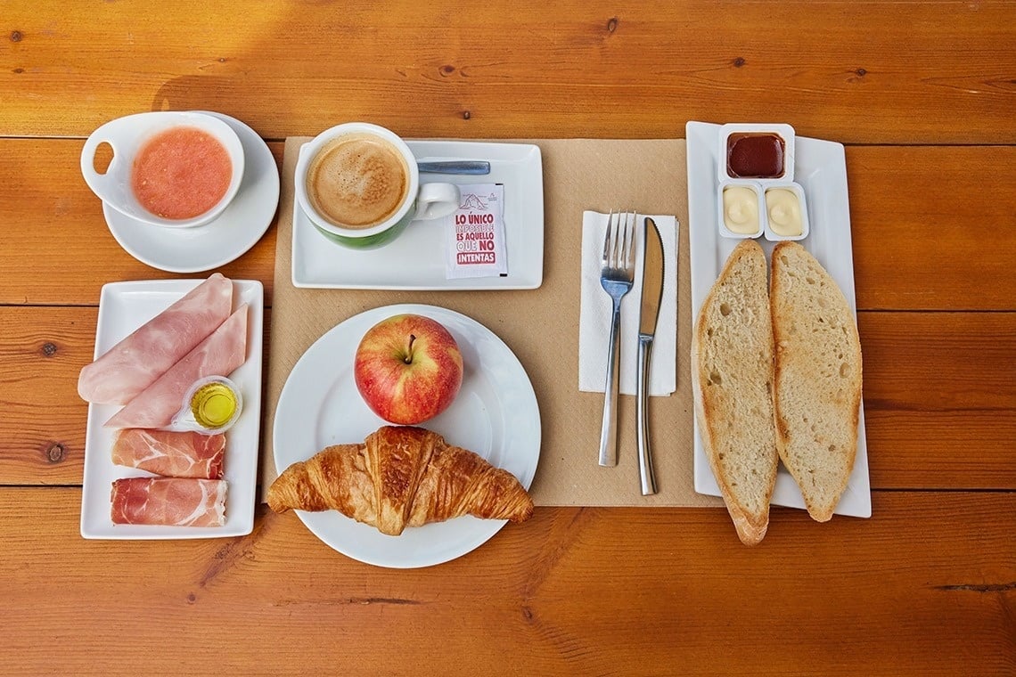 a wooden table topped with a variety of food including a croissant
