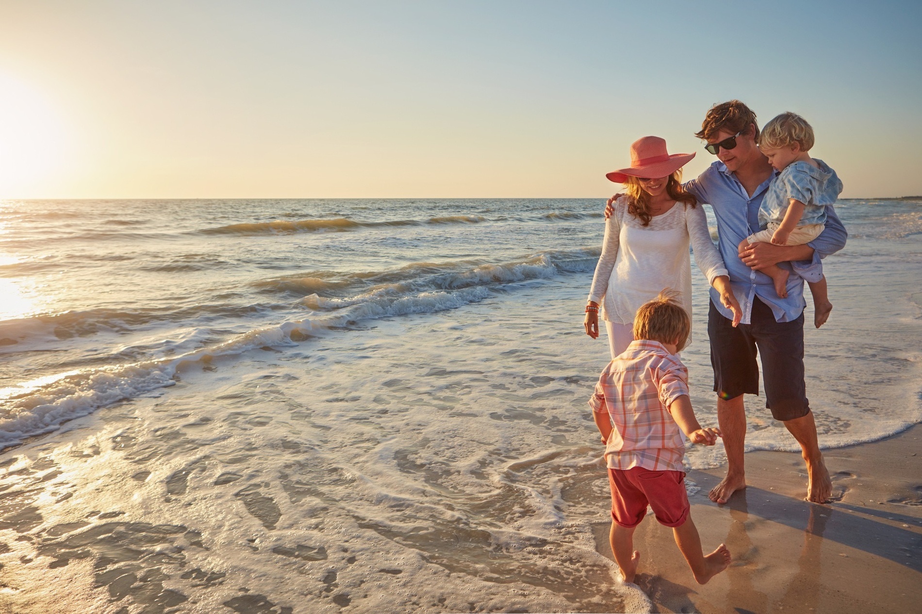 una família camina per la platja mirant el mar