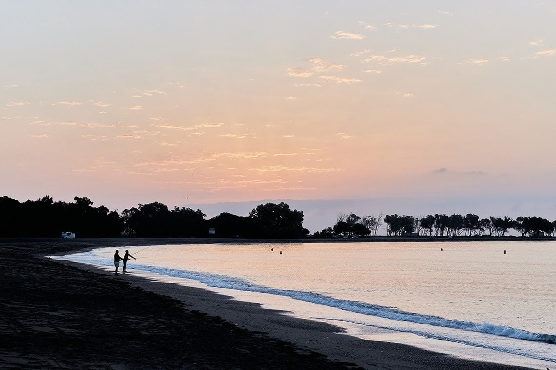 a swimming pool surrounded by chairs and umbrellas with mountains in the background