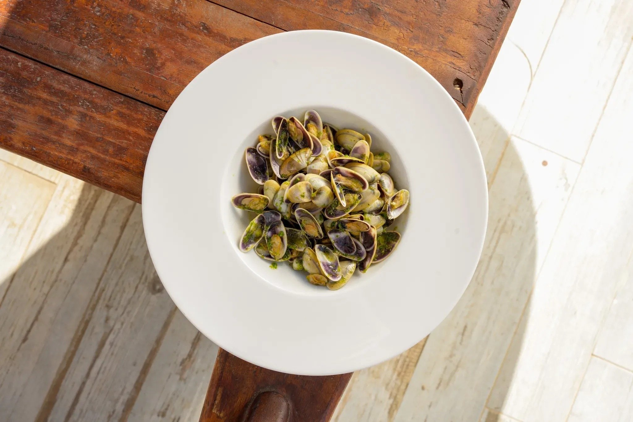 a bowl of clams sits on a wooden table