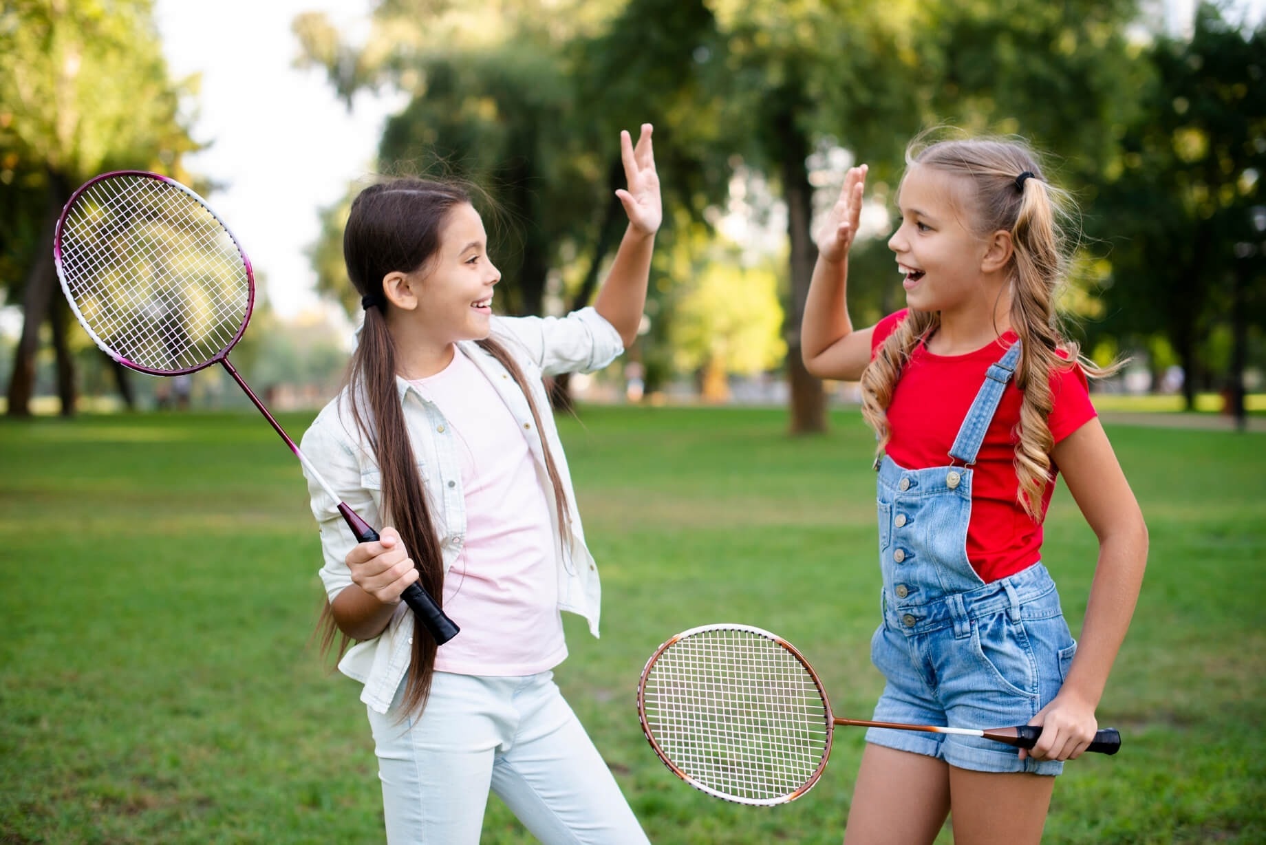 dues nenes jugant amb raquetes de badminton en un parc
