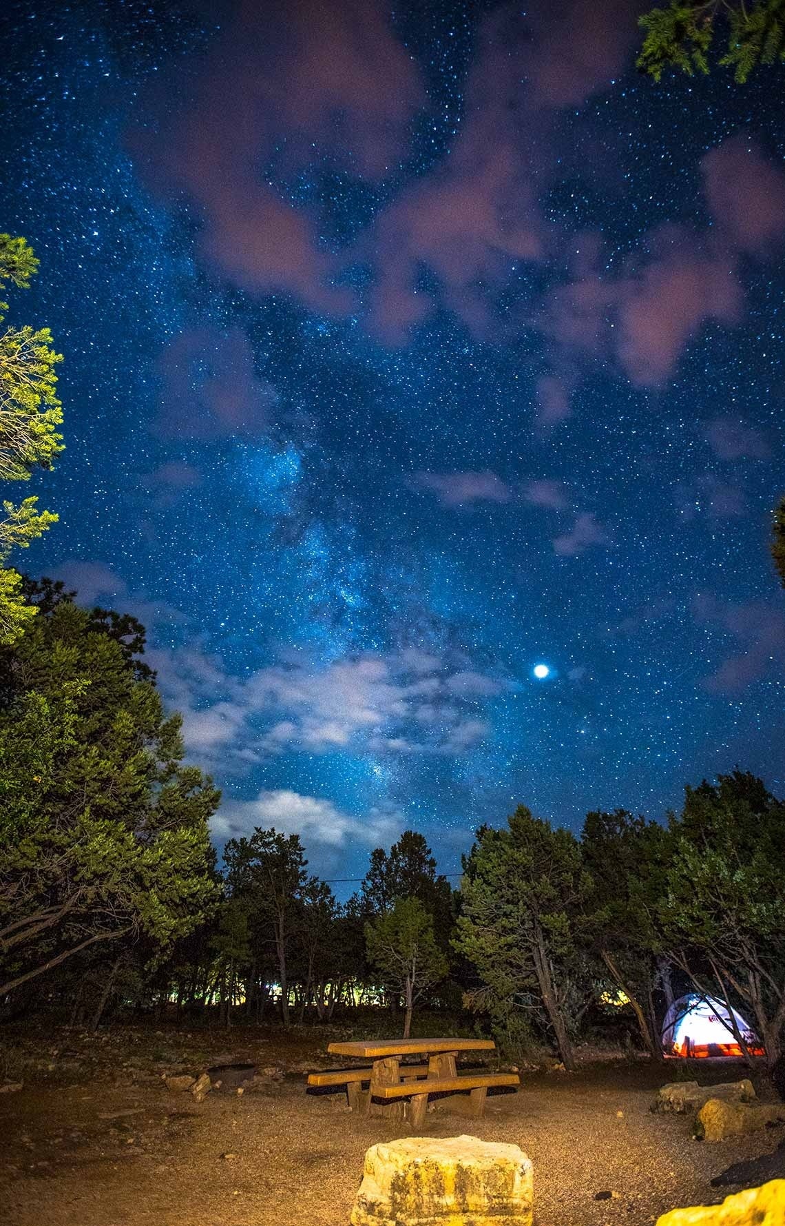 una tienda de campaña y una mesa de picnic bajo un cielo estrellado