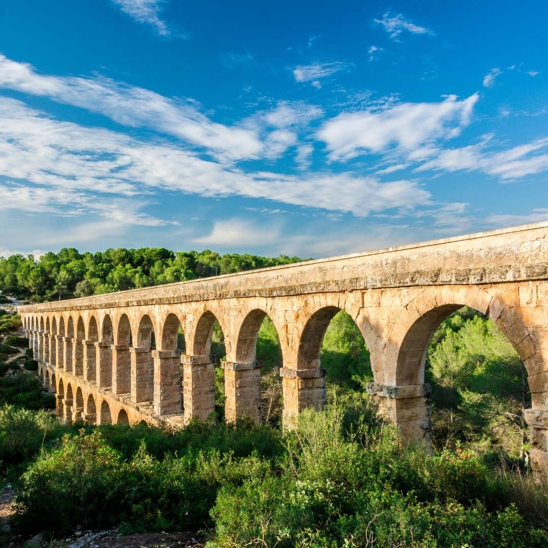 a stone bridge with arches and trees in the background