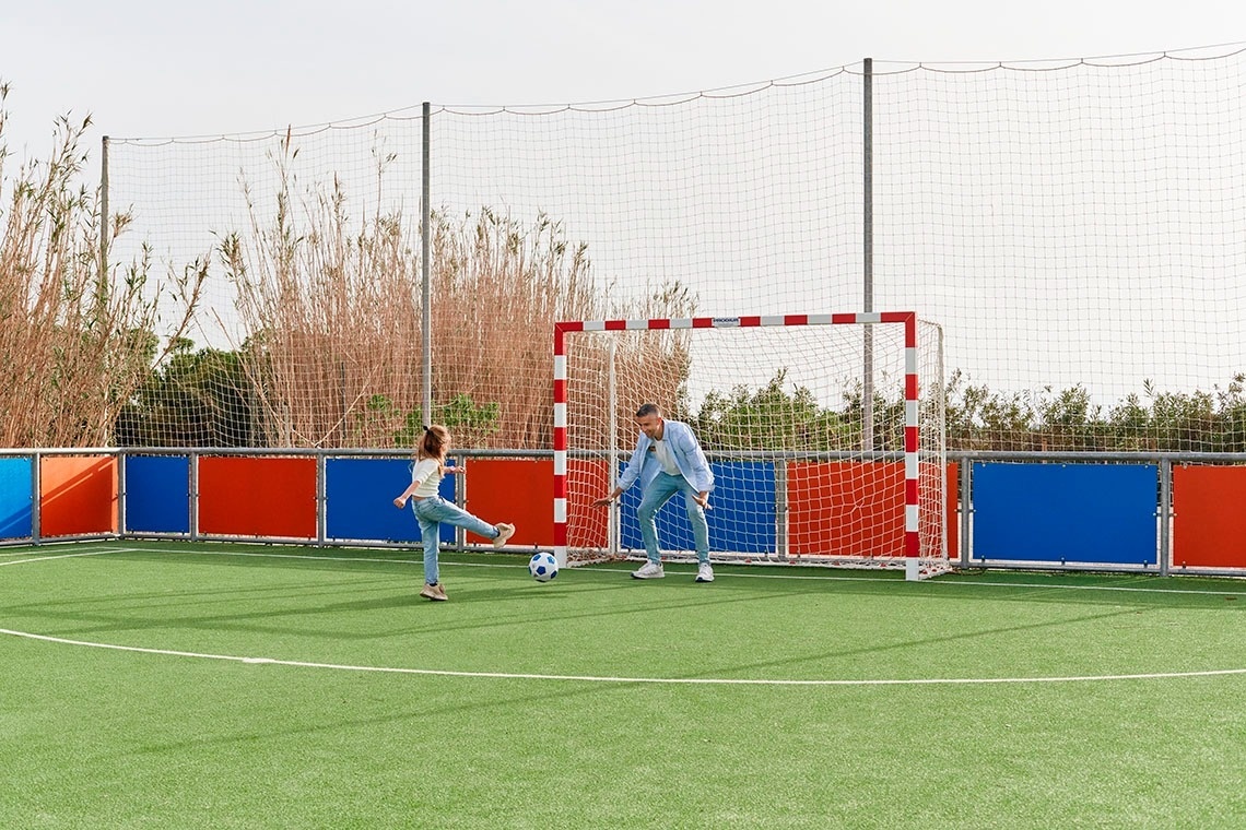 a man and a girl are playing soccer on a soccer field