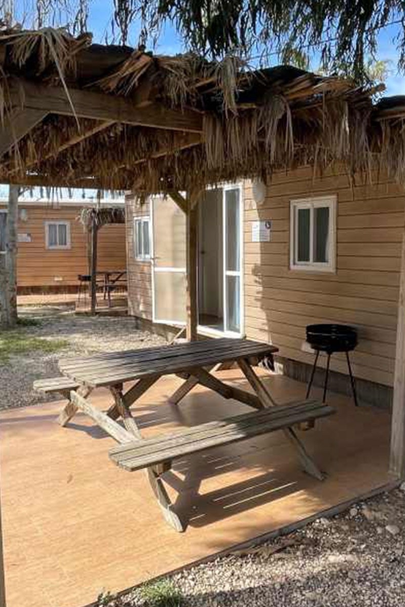 una mesa de picnic de madera i bancs a l' aire lliure .