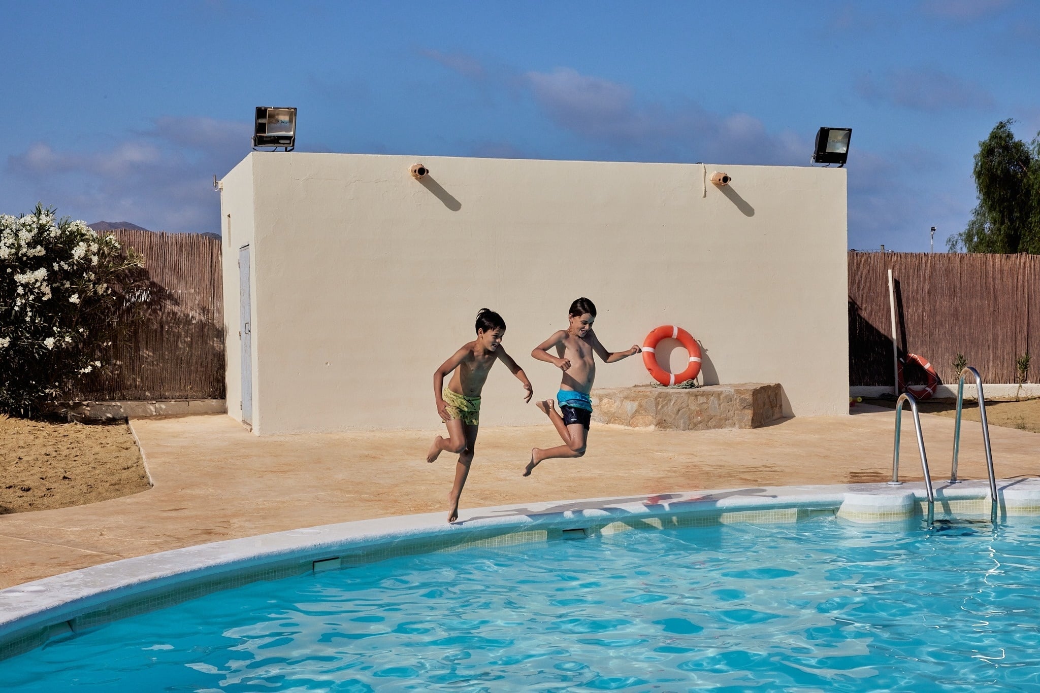 una piscina rodeada de palmeras y un edificio en el fondo
