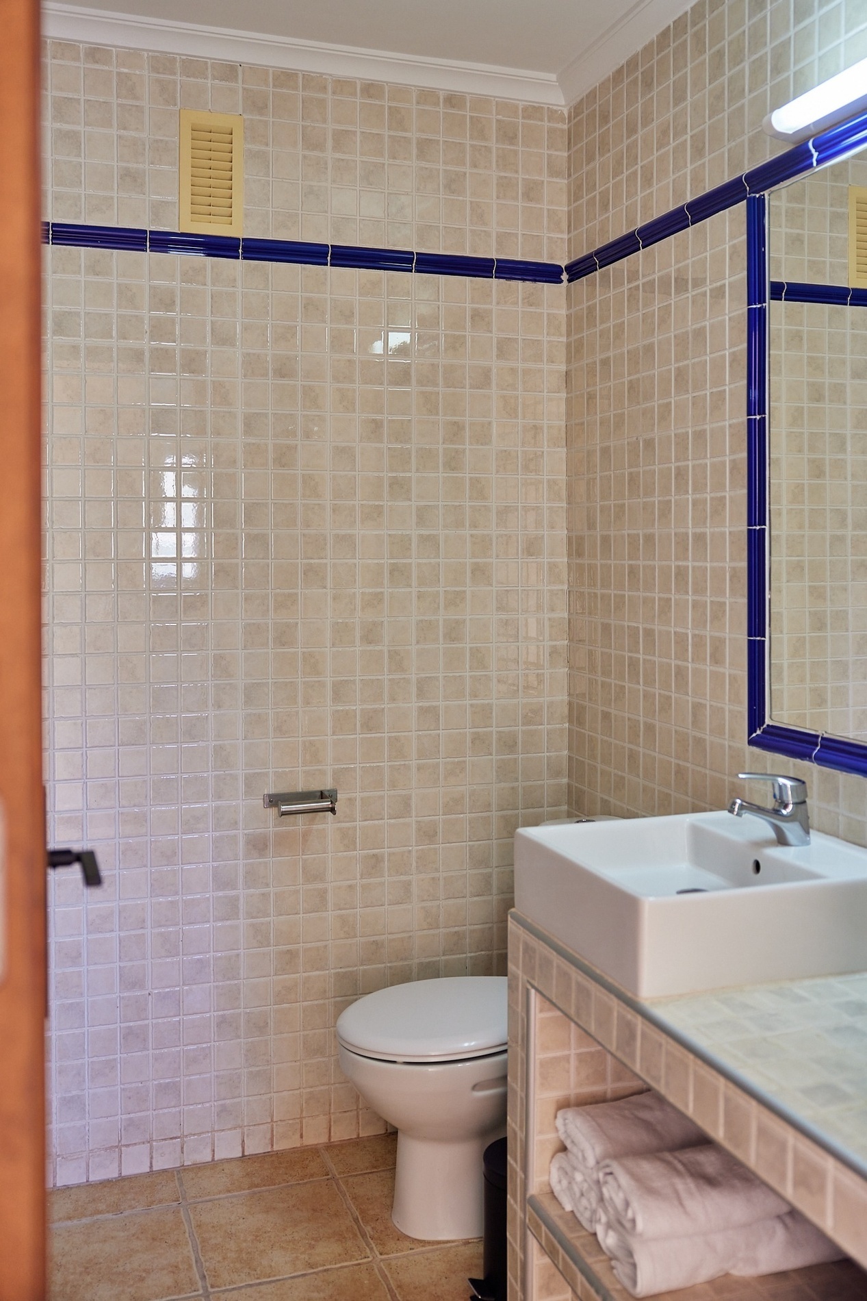 un baño con baldosas blancas y azules y un inodoro