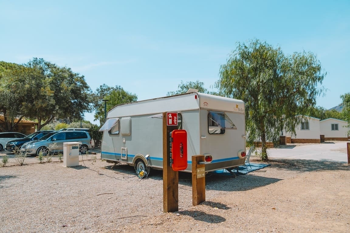 una caravana está estacionada junto a un poste de madera con una caja roja en la parte de atrás