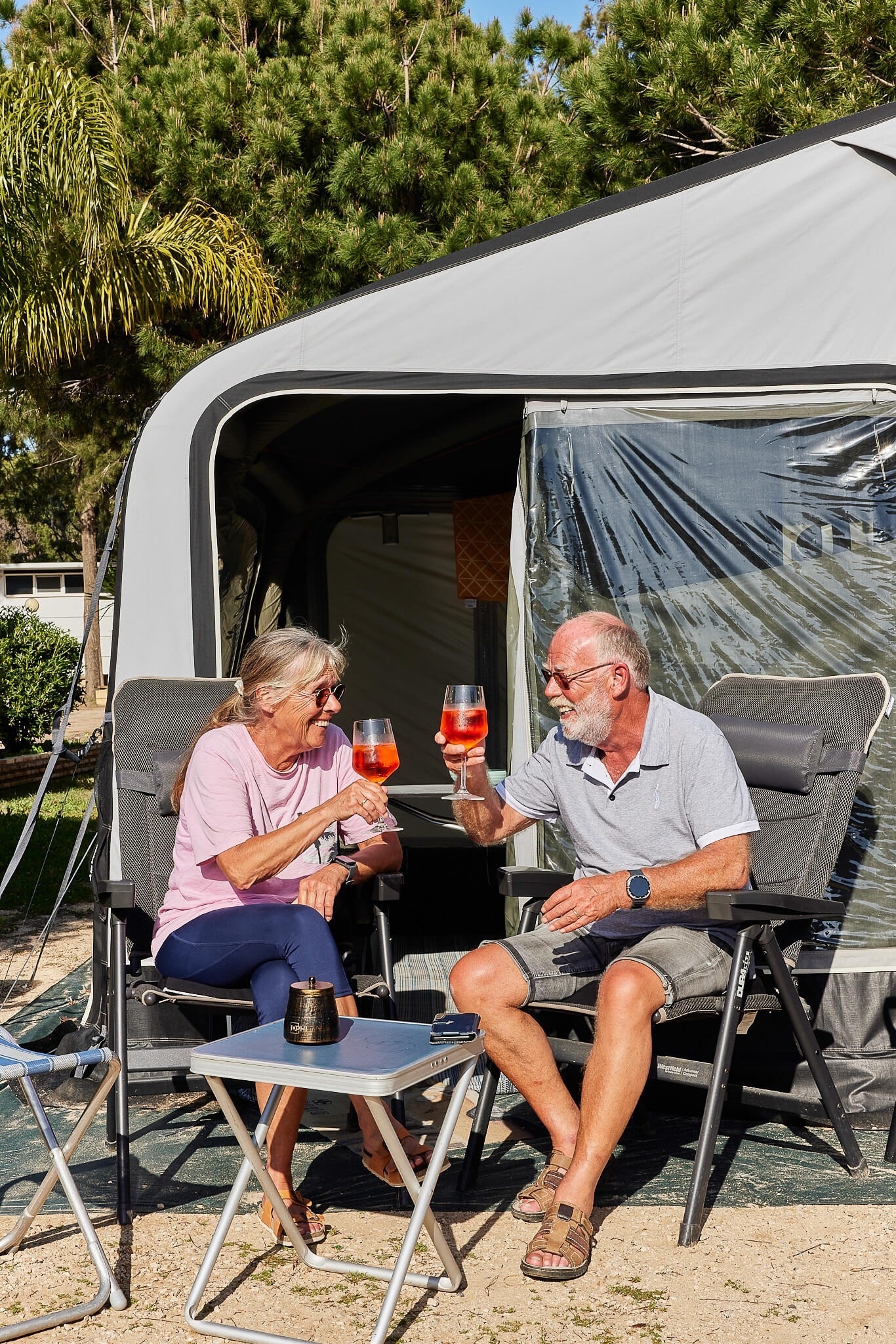 a man and woman toasting with wine glasses in front of a tent