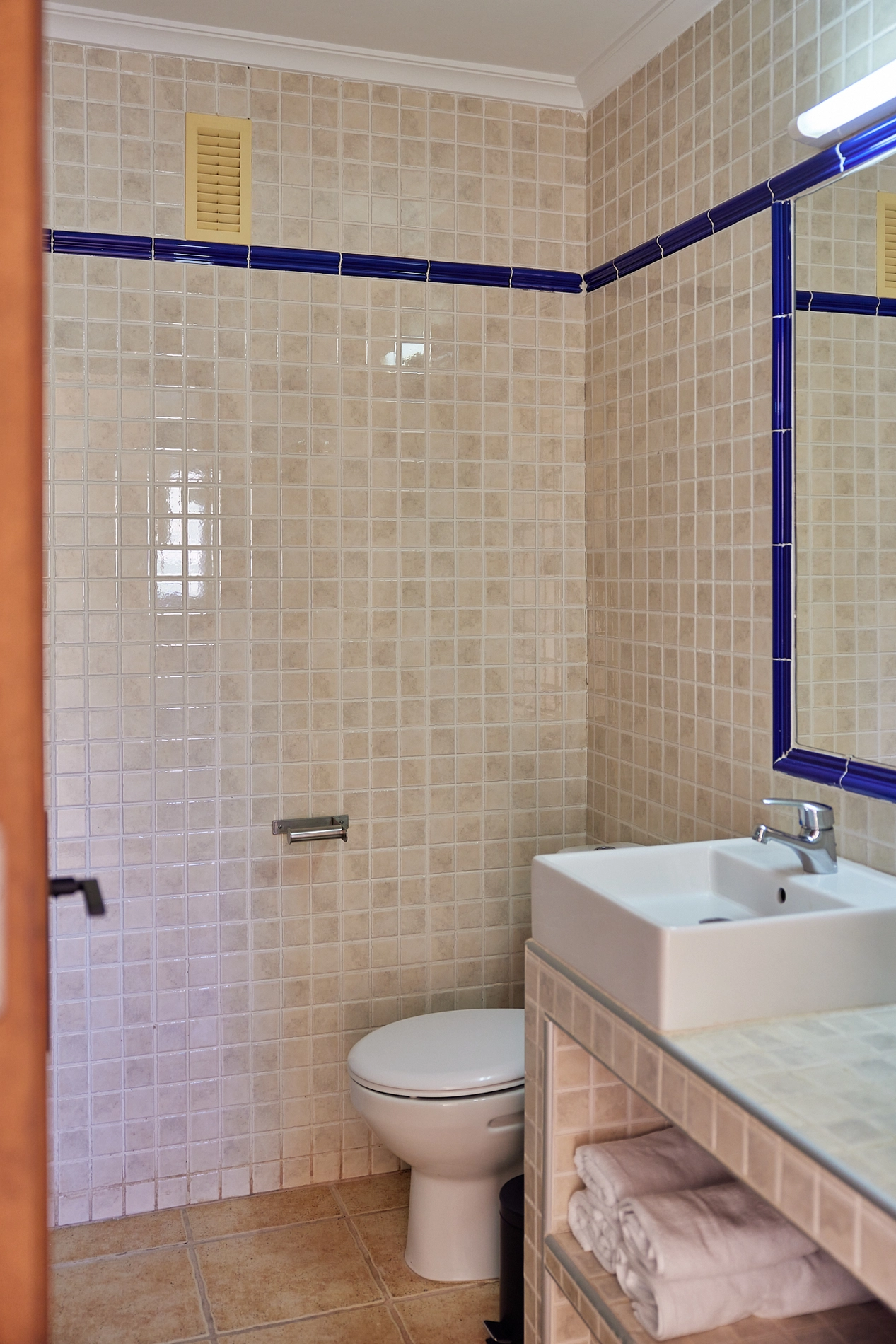 Baño con azulejos beige, lavabo moderno y toallas limpias. TAIGA Costa Calida