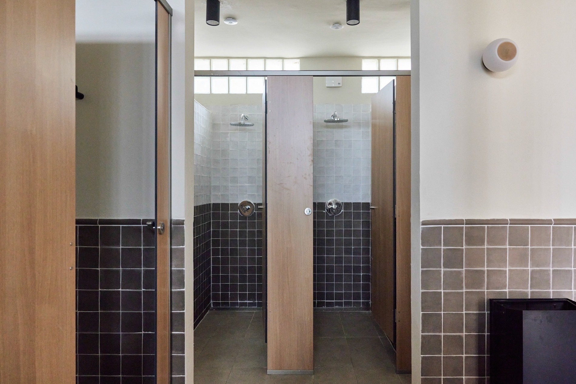 un baño con azulejos negros y puertas de madera