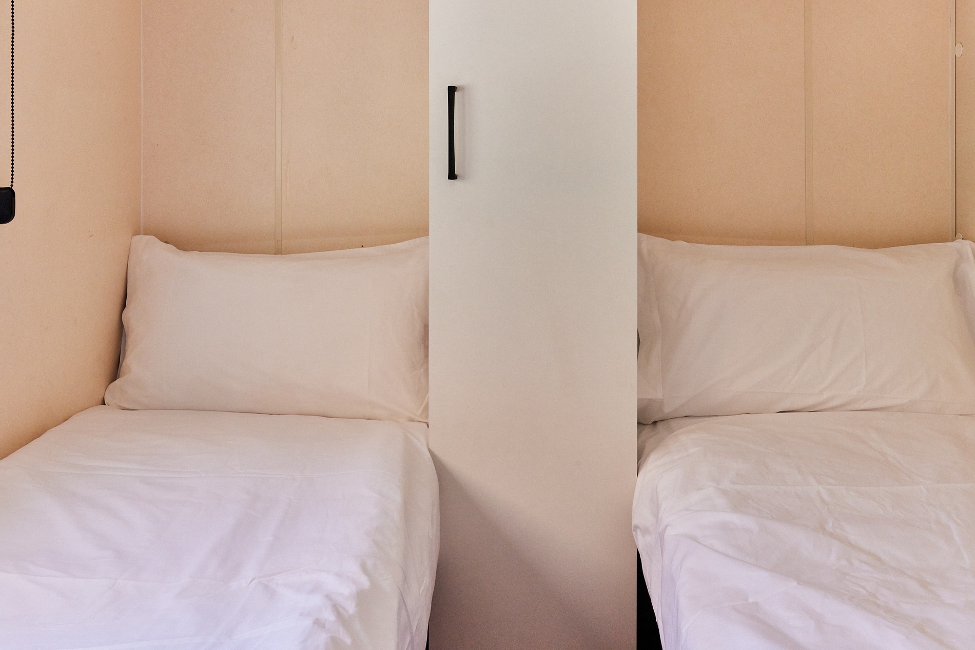 two beds in a room with white sheets and pillows