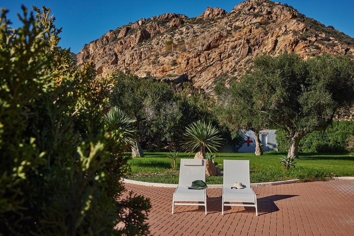 two lounge chairs in front of a mountain with a cross painted on it