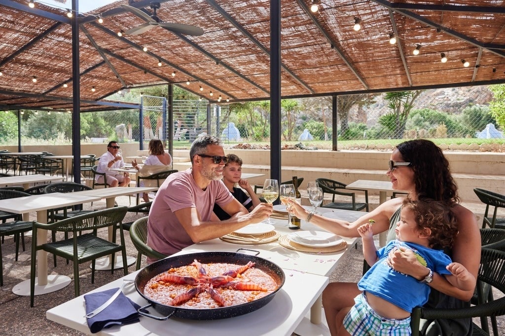 a group of people sit at tables outside a building with a sign that says bar