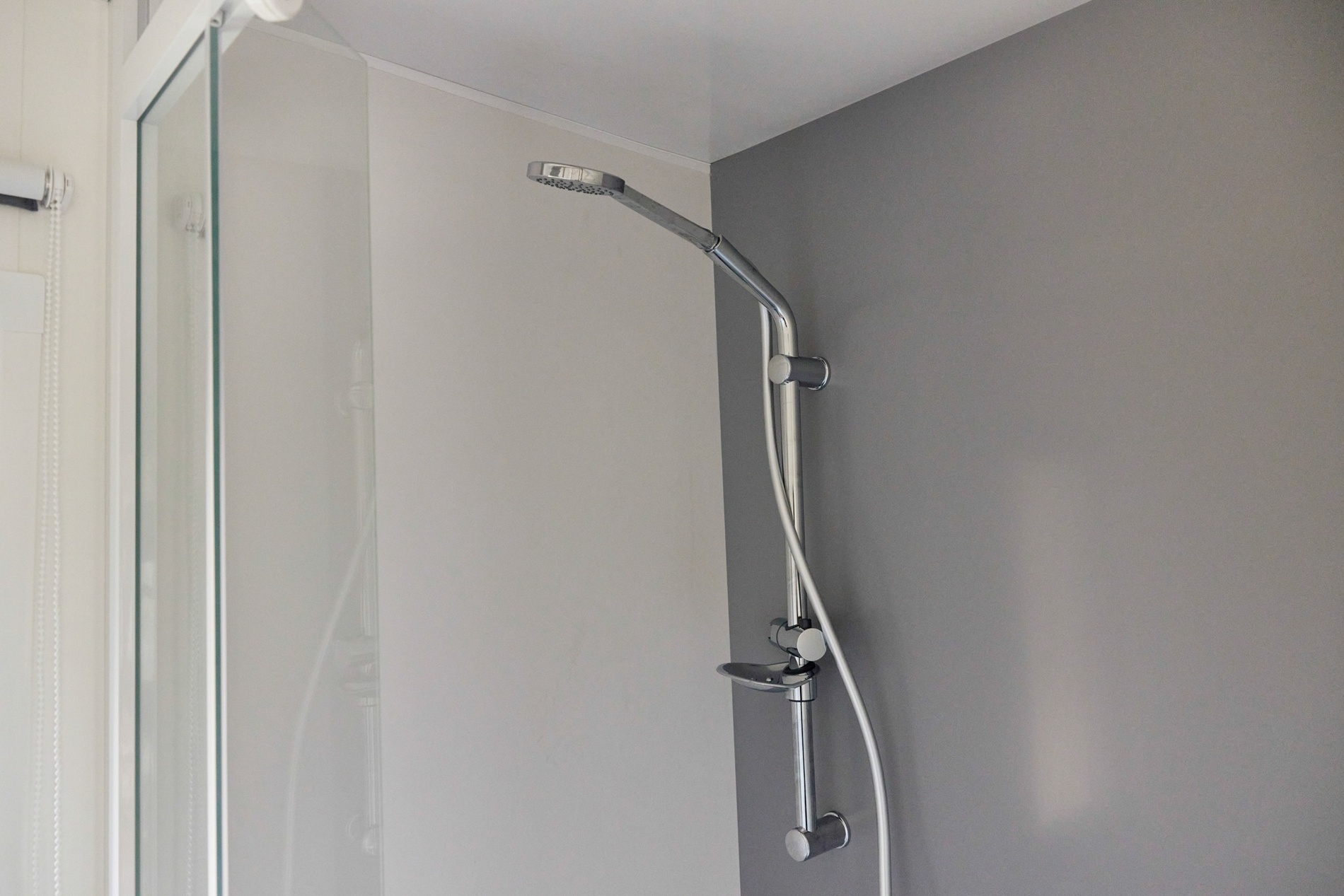 eine Dusche in einem Badezimmer mit einer grauen Wand