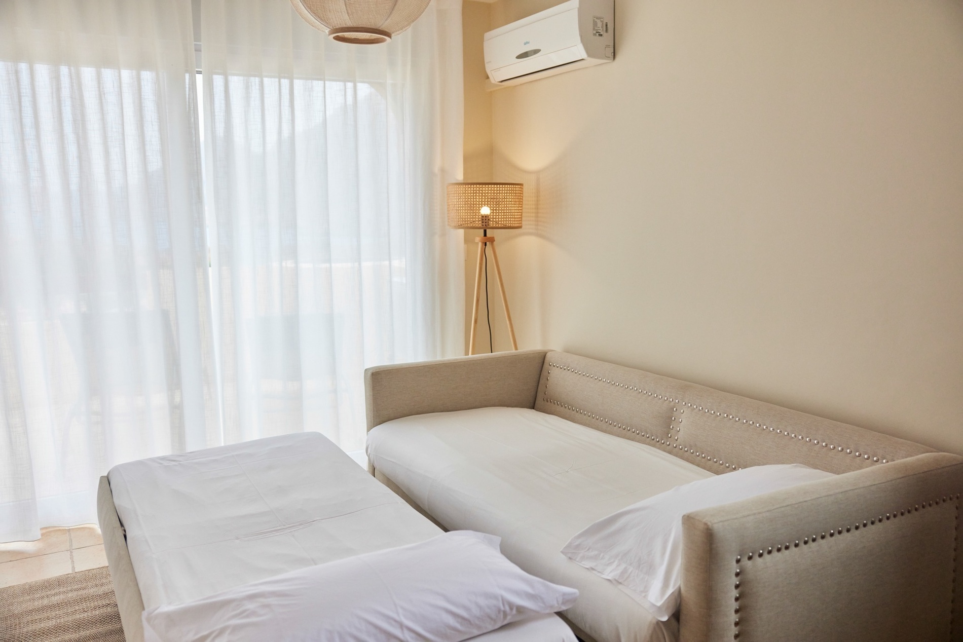 un sofá y una lámpara en una habitación con cortinas blancas