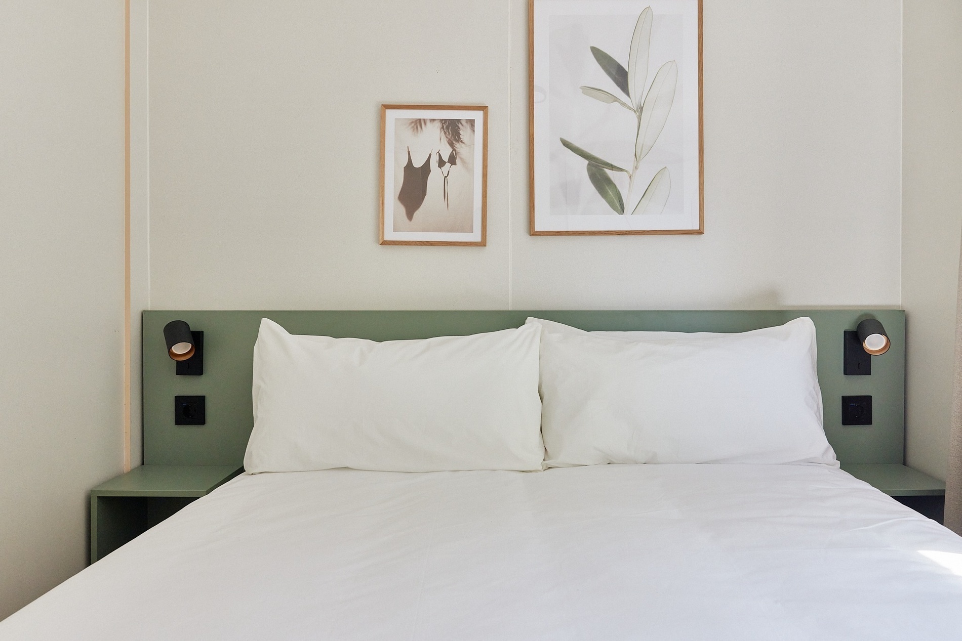 a bedroom with a bed and two pictures on the wall above it