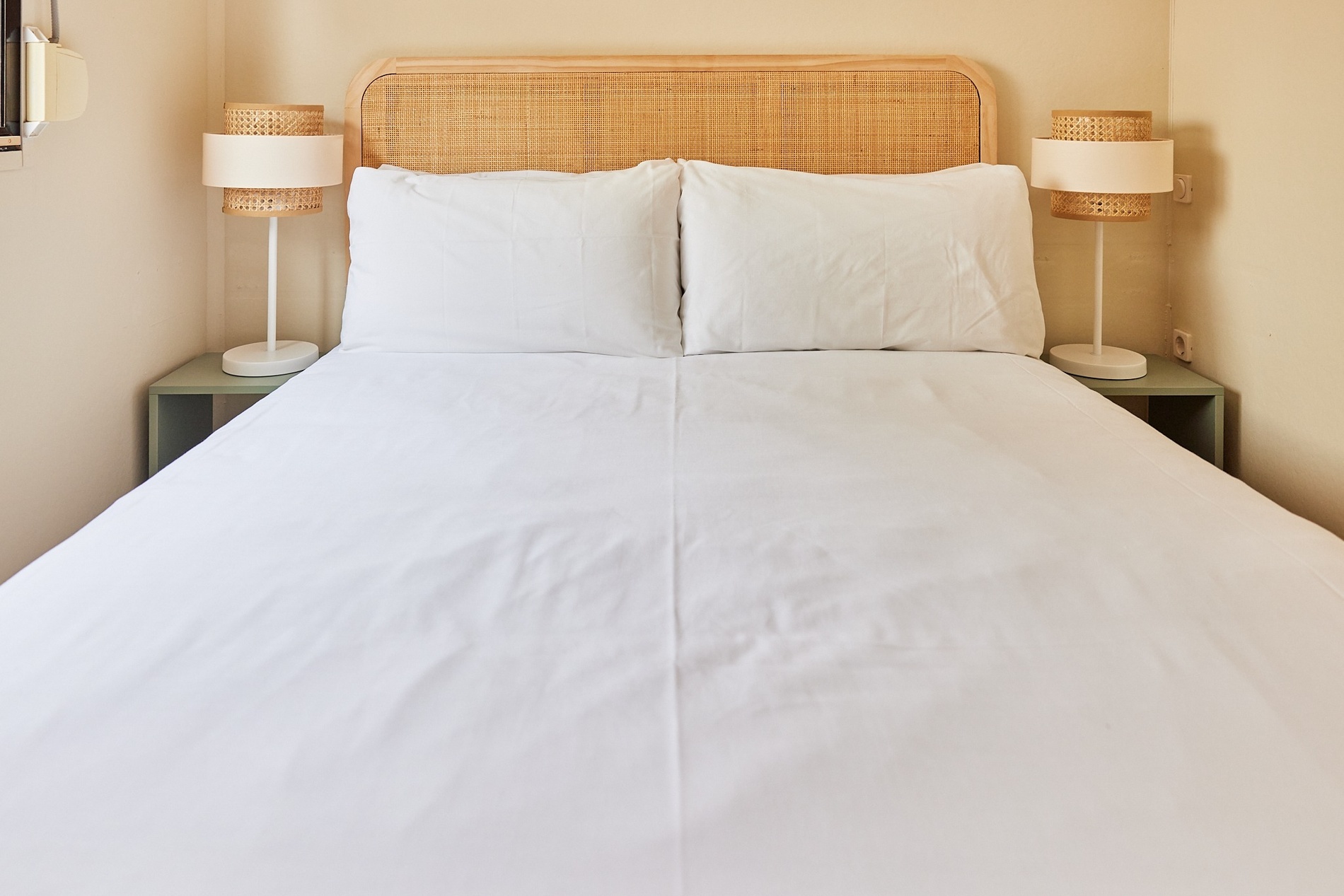 a bed with two lamps next to it and a wicker headboard