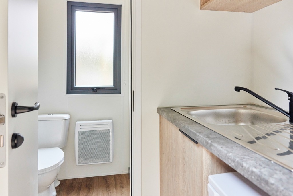 un baño con un inodoro y un fregadero junto a una ventana