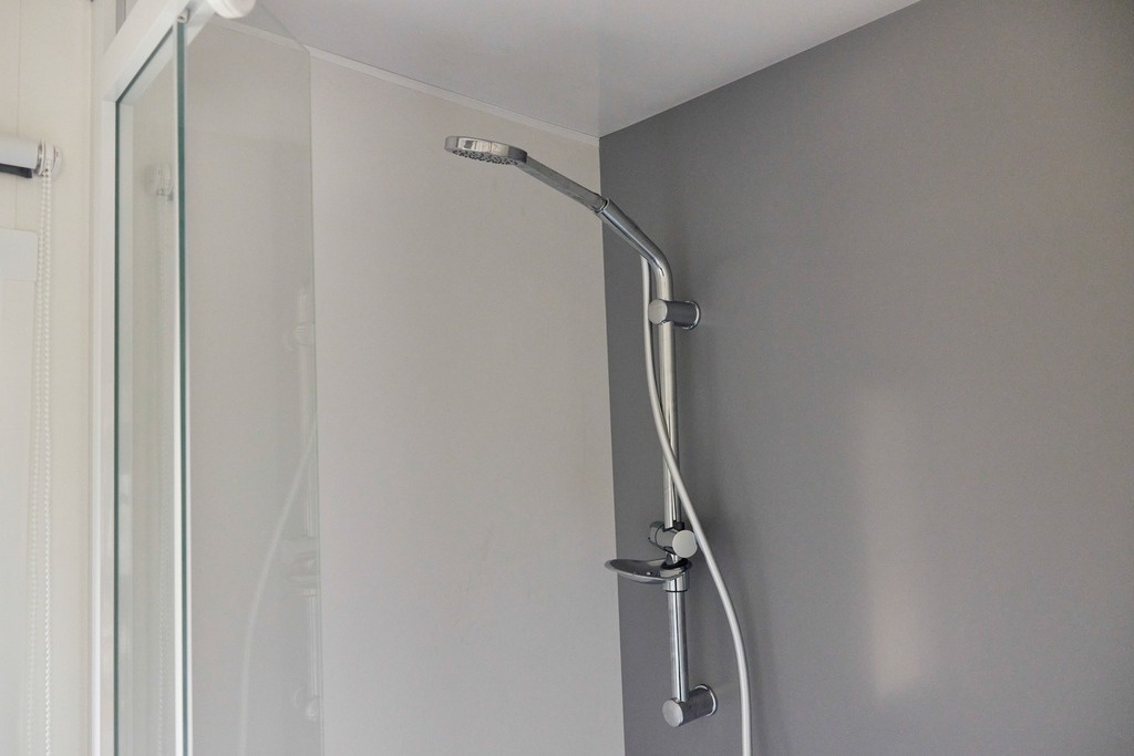 una ducha en un baño con una pared gris