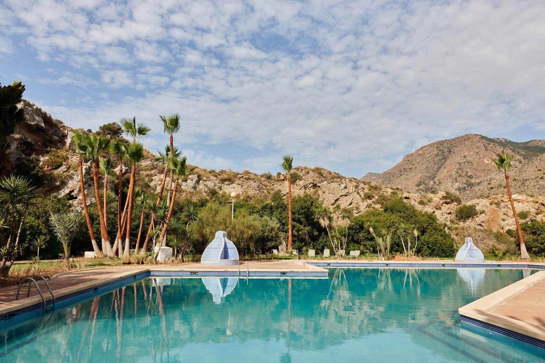 une piscine avec des palmiers et des montagnes en arrière-plan