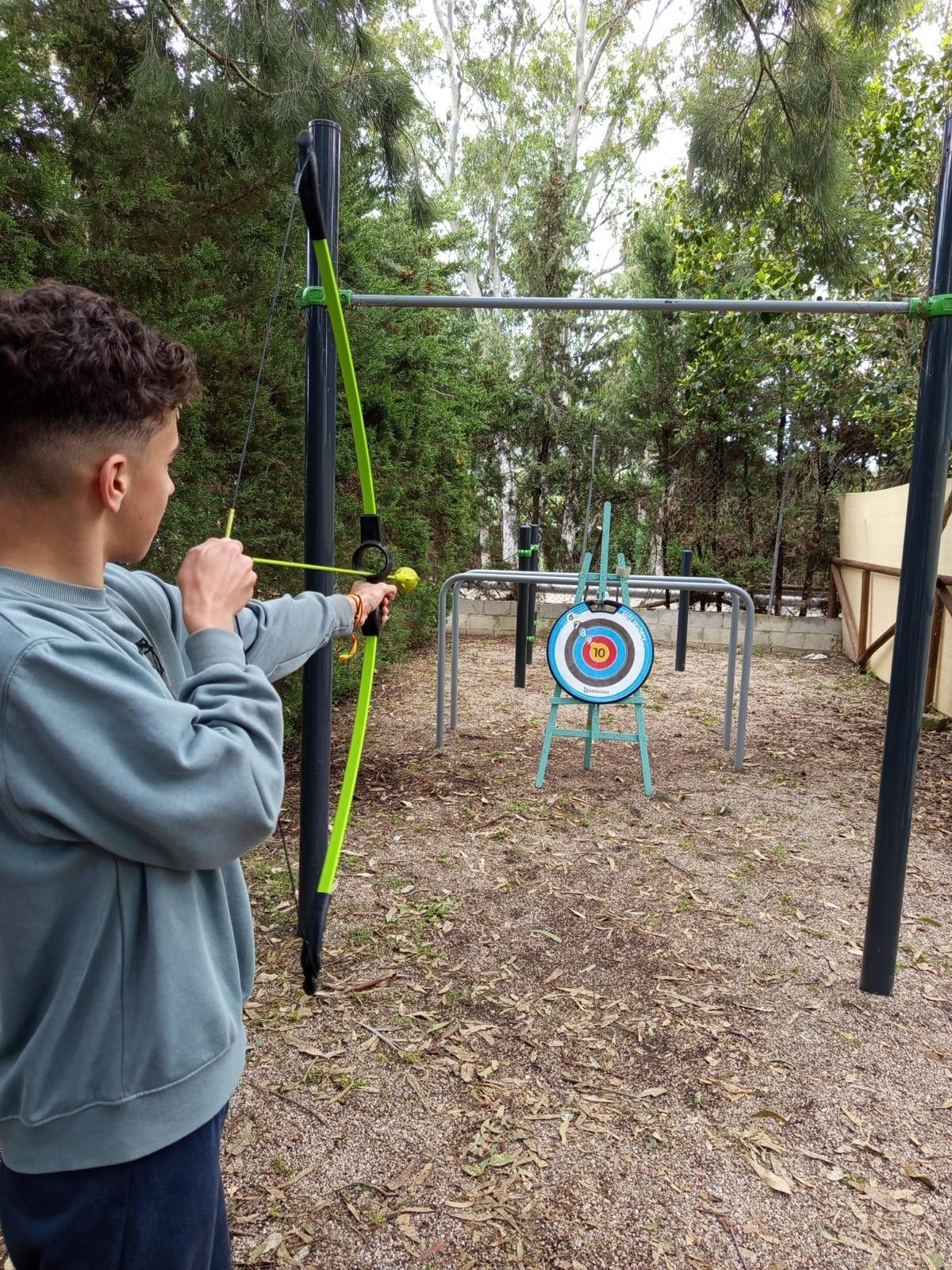 un jove apunta a un objectiu amb un arc i una flecha