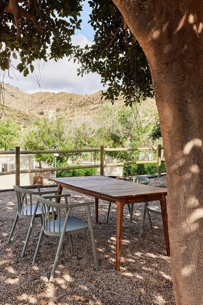 a table and chairs under a tree in a gravel area