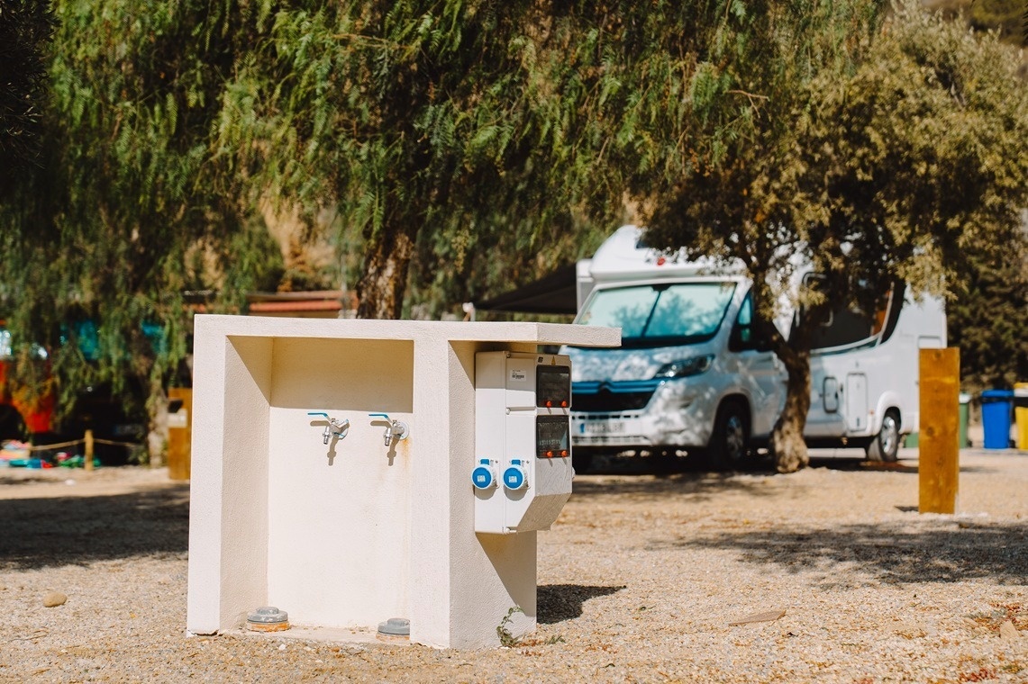 un rv blanco está estacionado junto a una fuente de agua