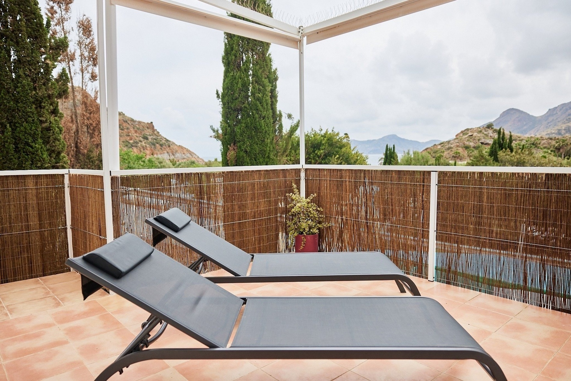 two lounge chairs on a balcony with mountains in the background