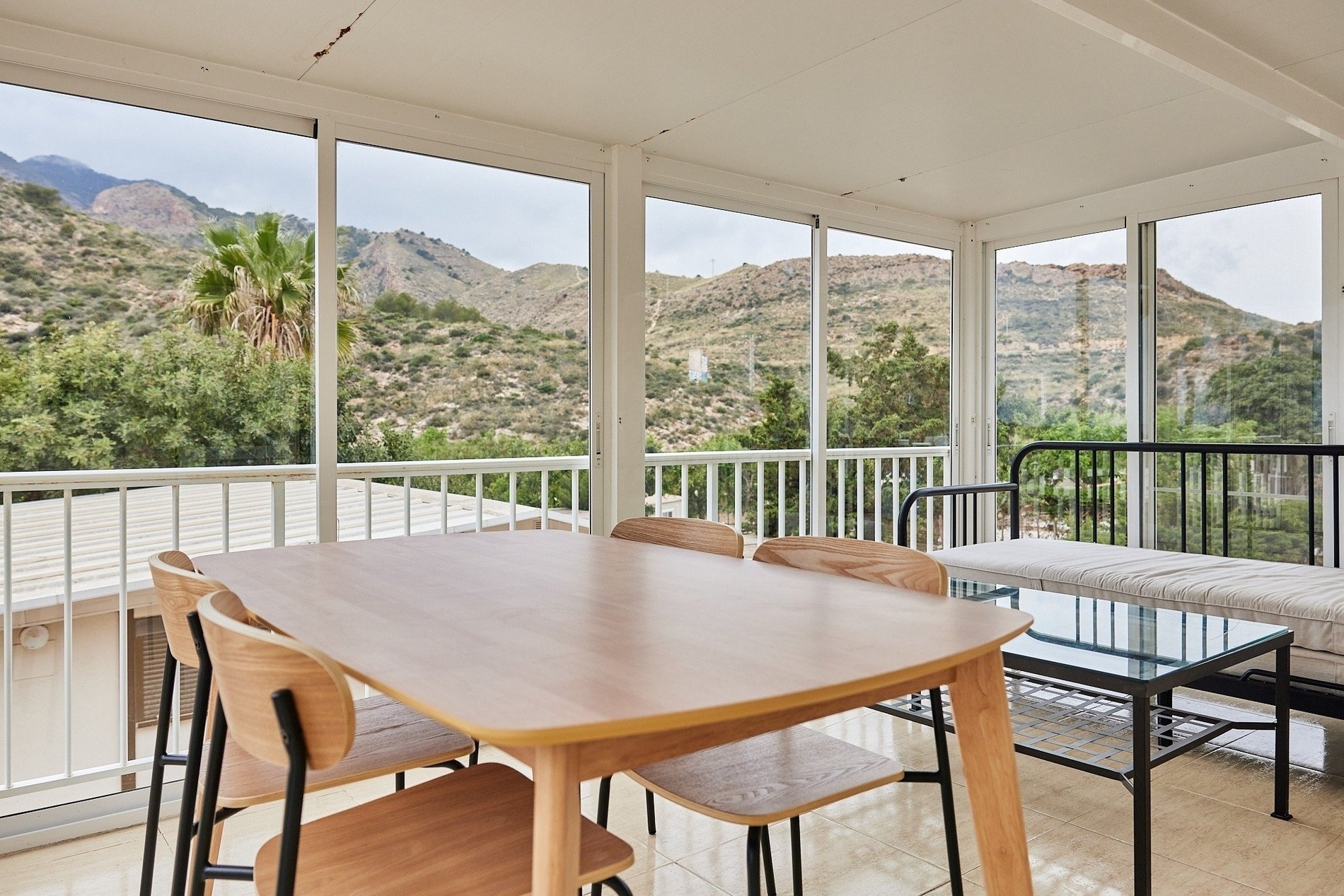 a table and chairs in a room with mountains in the background