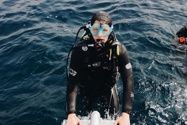 a scuba diver wearing a wetsuit and goggles is standing in the water