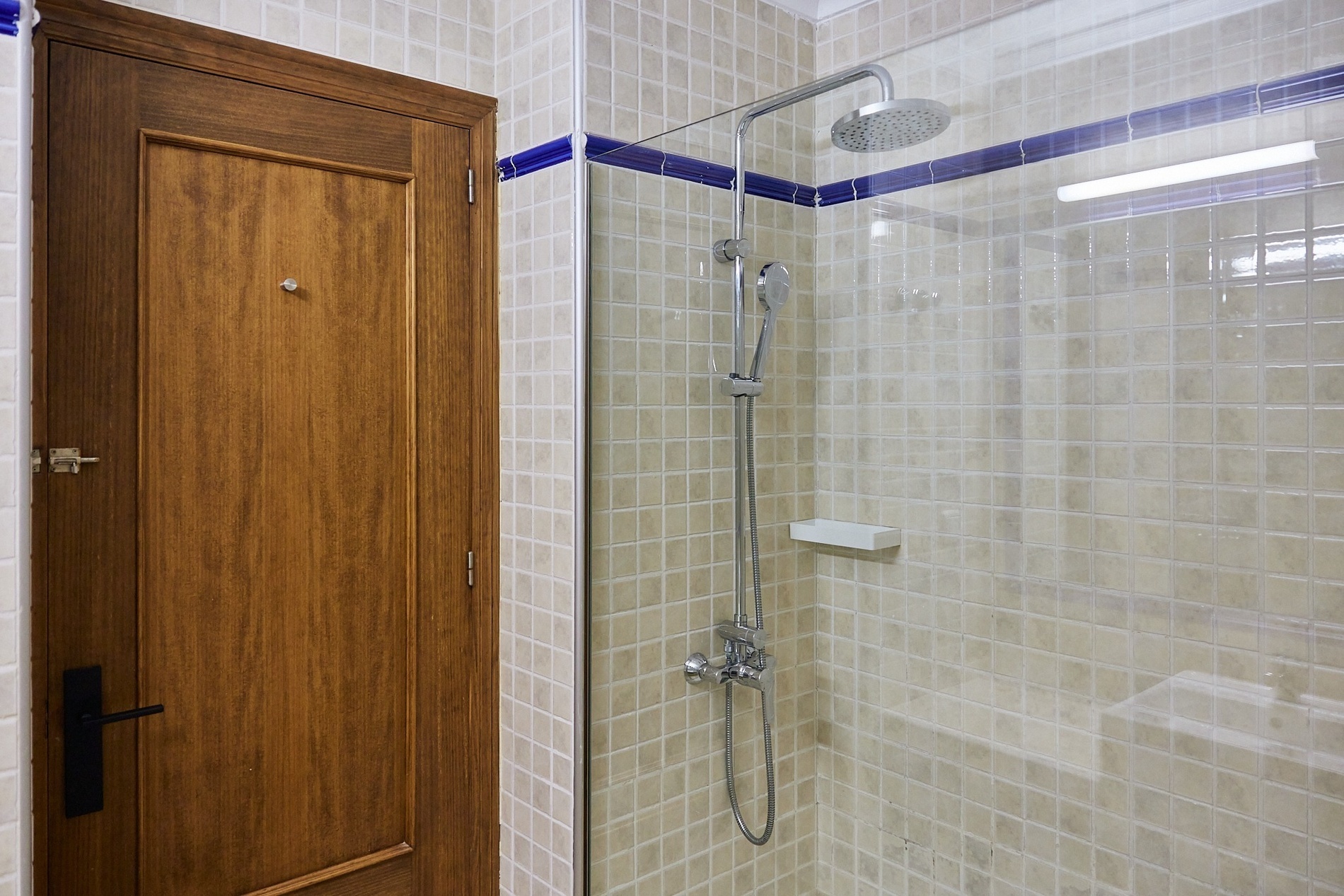 una ducha en un baño con una puerta de madera