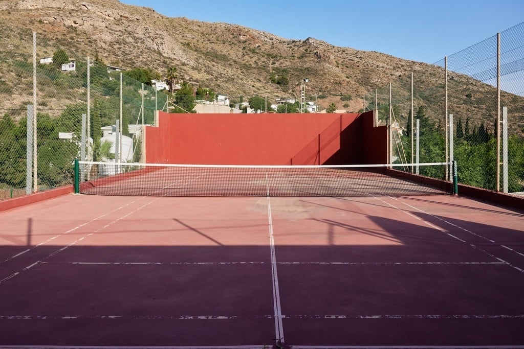 ein Mann hält einen Tennisschläger auf einem Tennisplatz