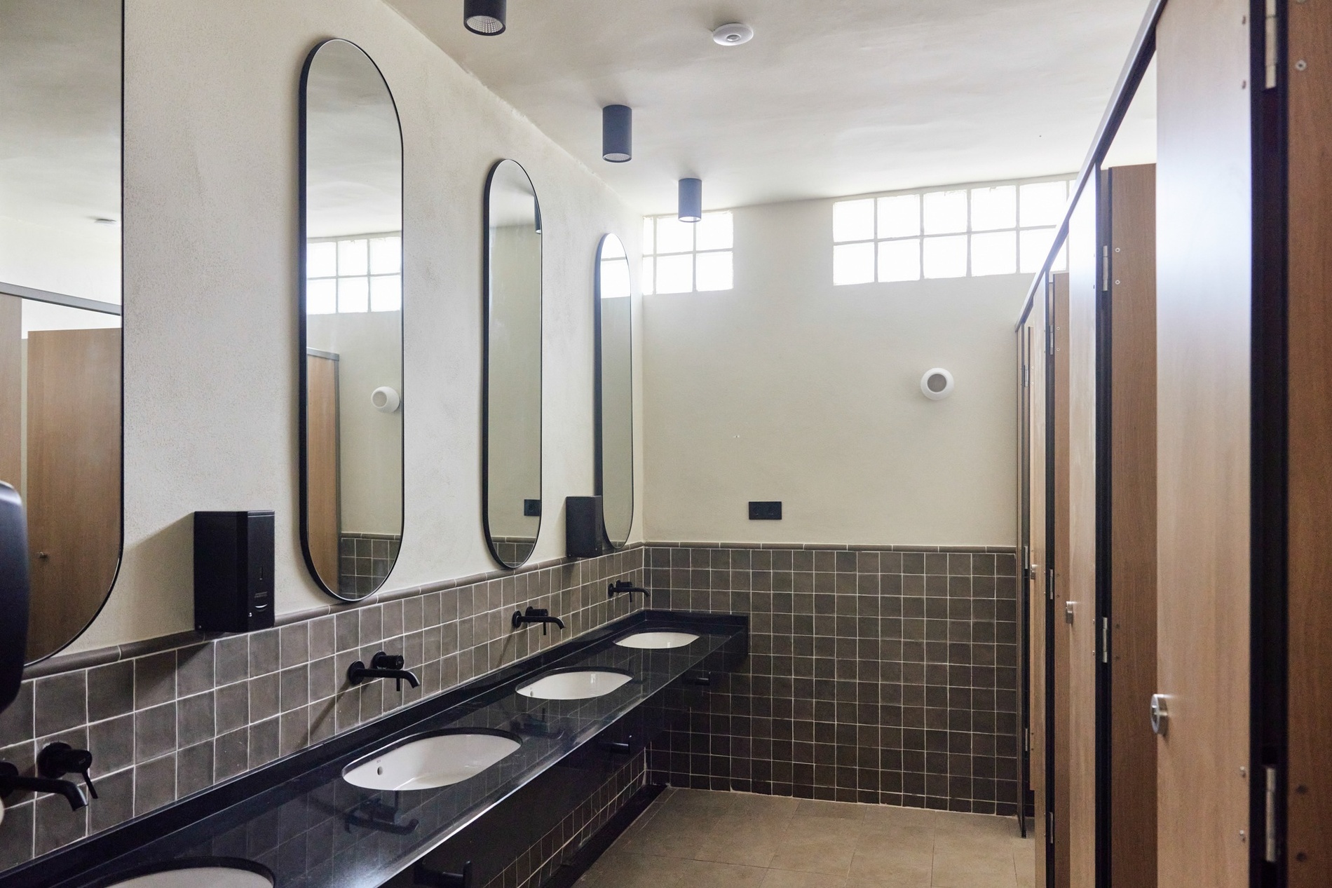 un baño con lavabos y espejos y un dispensador de jabón