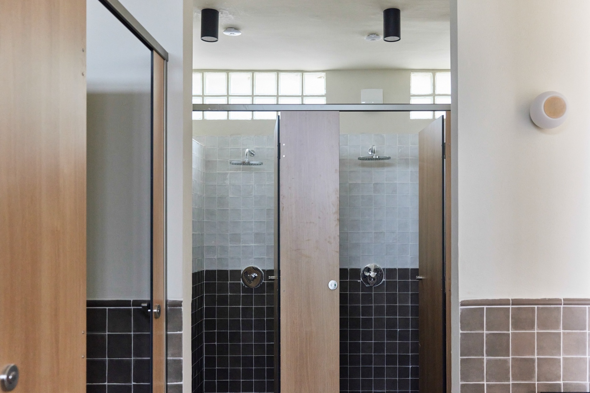 un baño con azulejos negros y puertas de madera