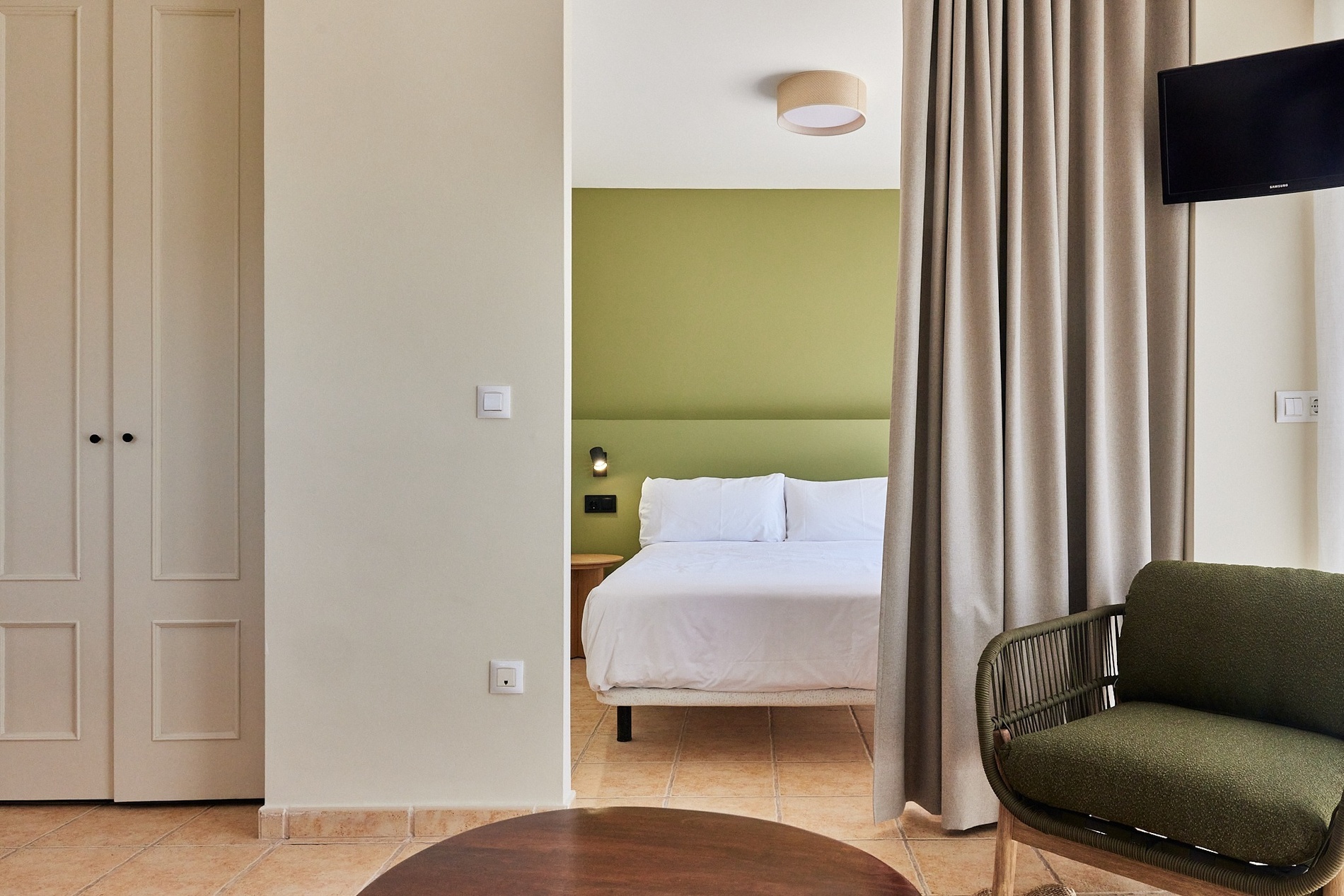 una habitación con una cama blanca y una silla verde