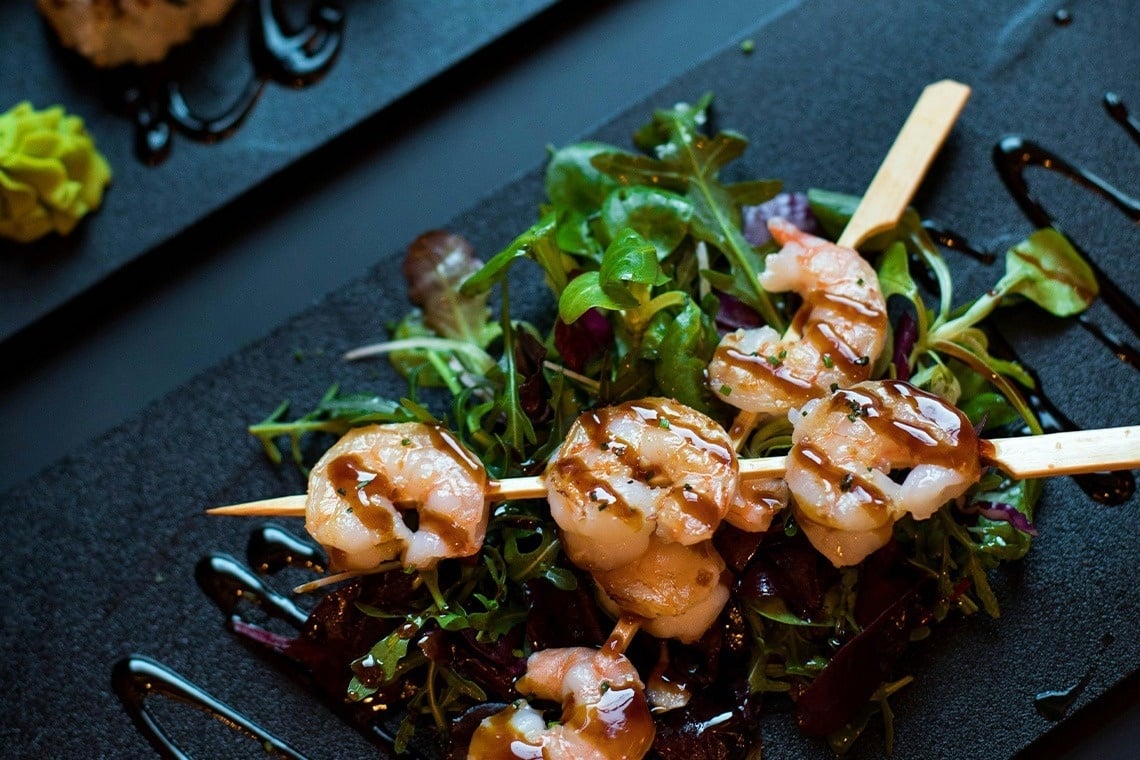 Garnelen auf einem Holzspieß mit Salat und Soße