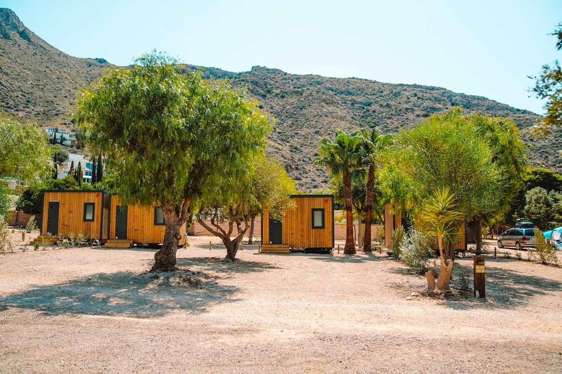 una fila de pequeñas cabañas de madera están rodeadas de árboles y montañas