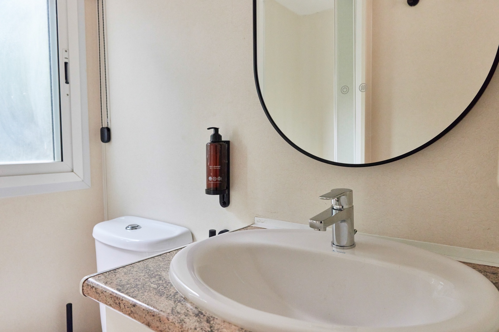 a bathroom sink with a soap dispenser on the wall