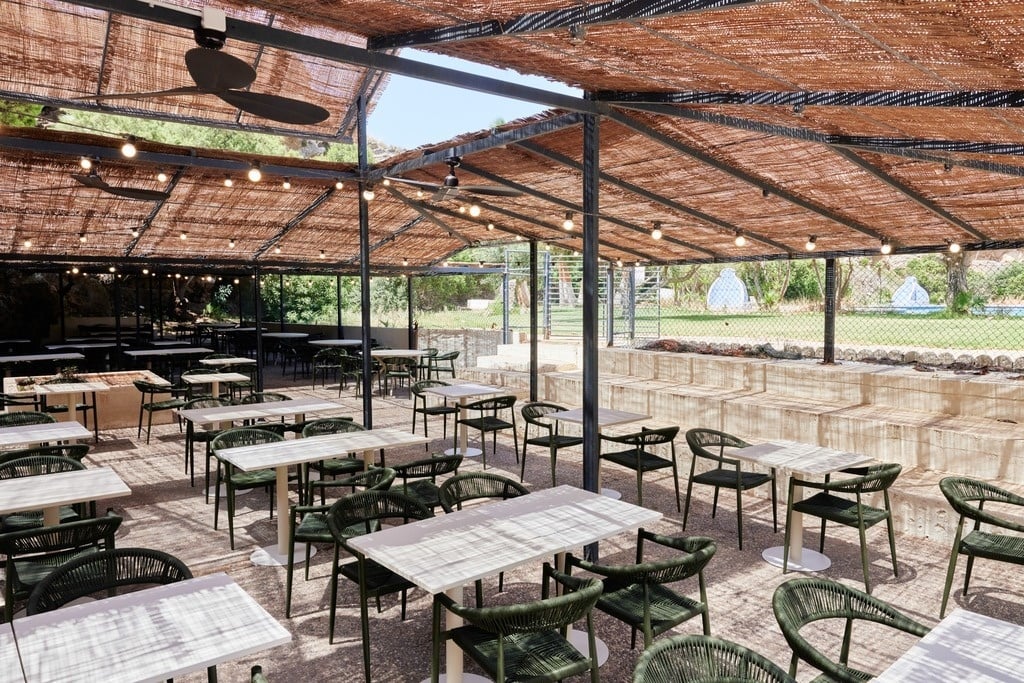 a group of people sit at tables outside a building with a sign that says bar