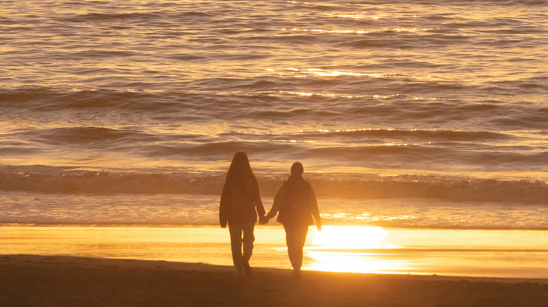 una mujer está sentada en la playa haciendo un corazón con sus manos