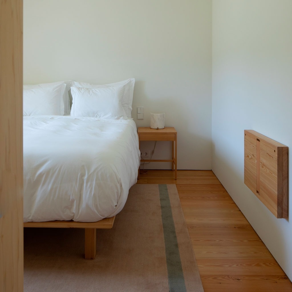 um quarto com cama e mesa de cabeceira de madeira