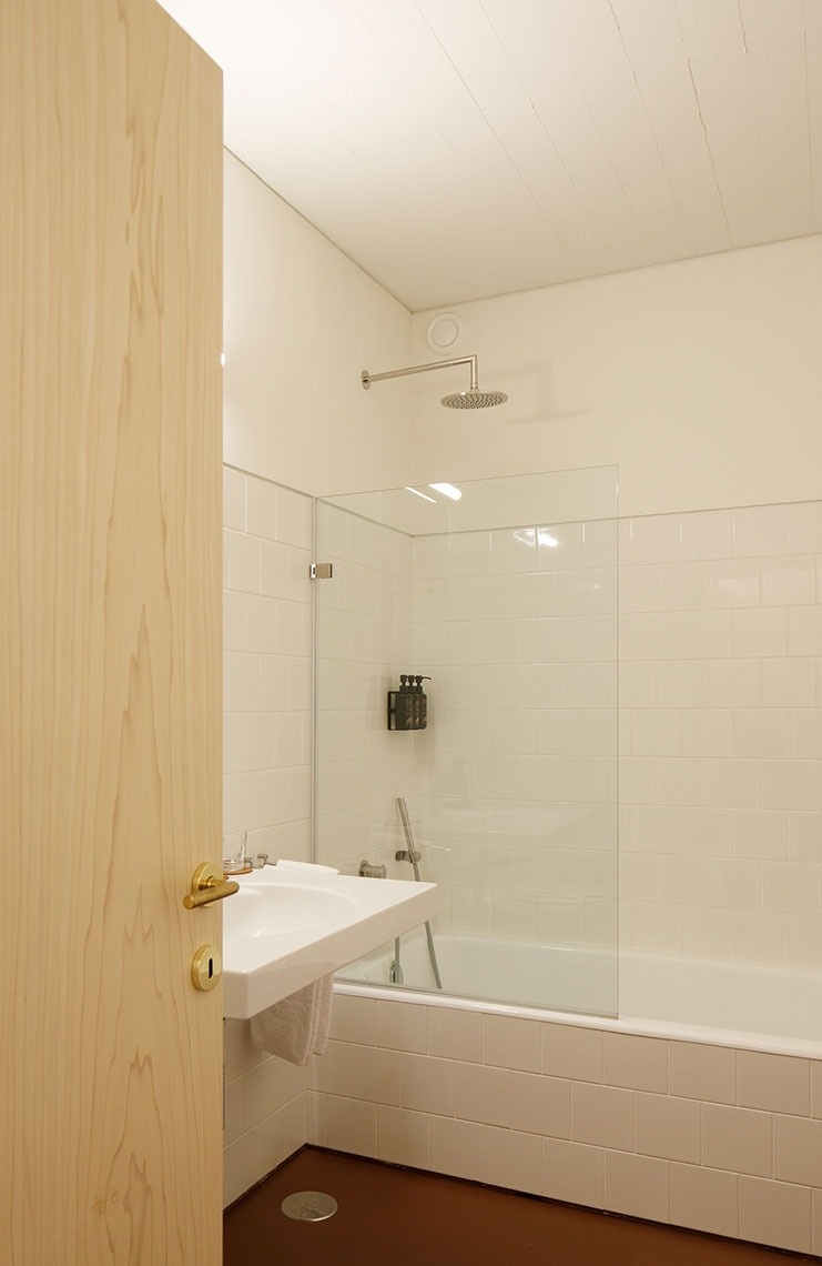 um banheiro com pia e banheira e porta de vidro