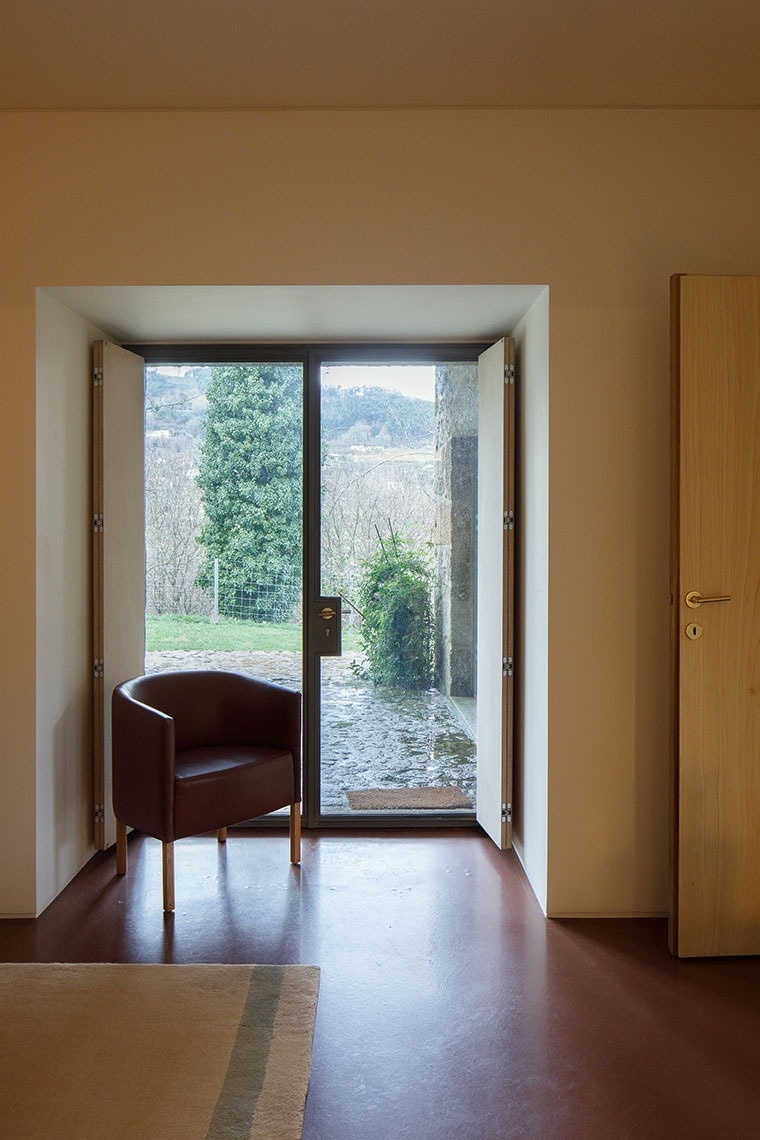 uma cadeira de couro marrom está em frente a uma porta de vidro