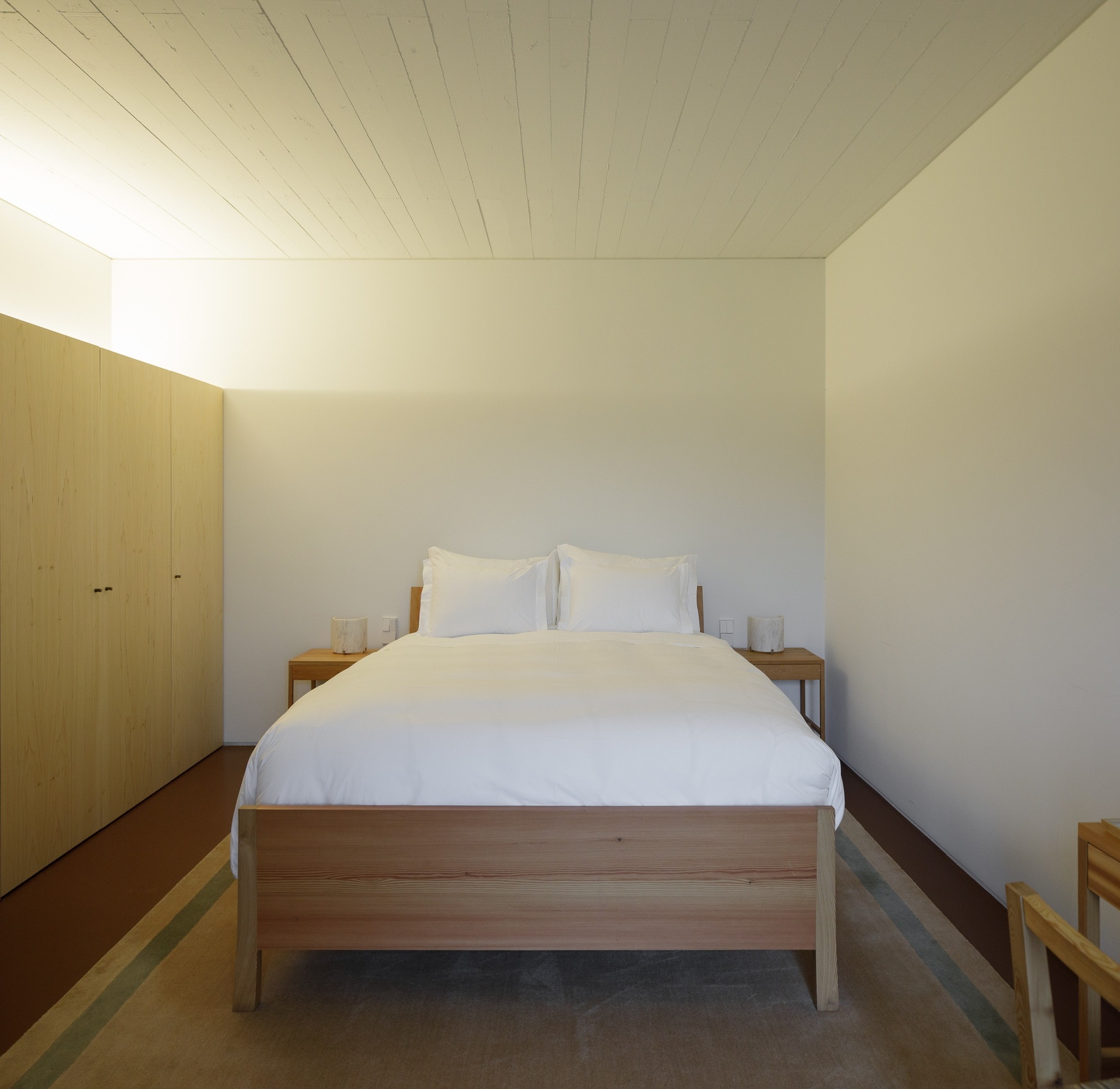 um quarto com cama de madeira e travesseiros brancos