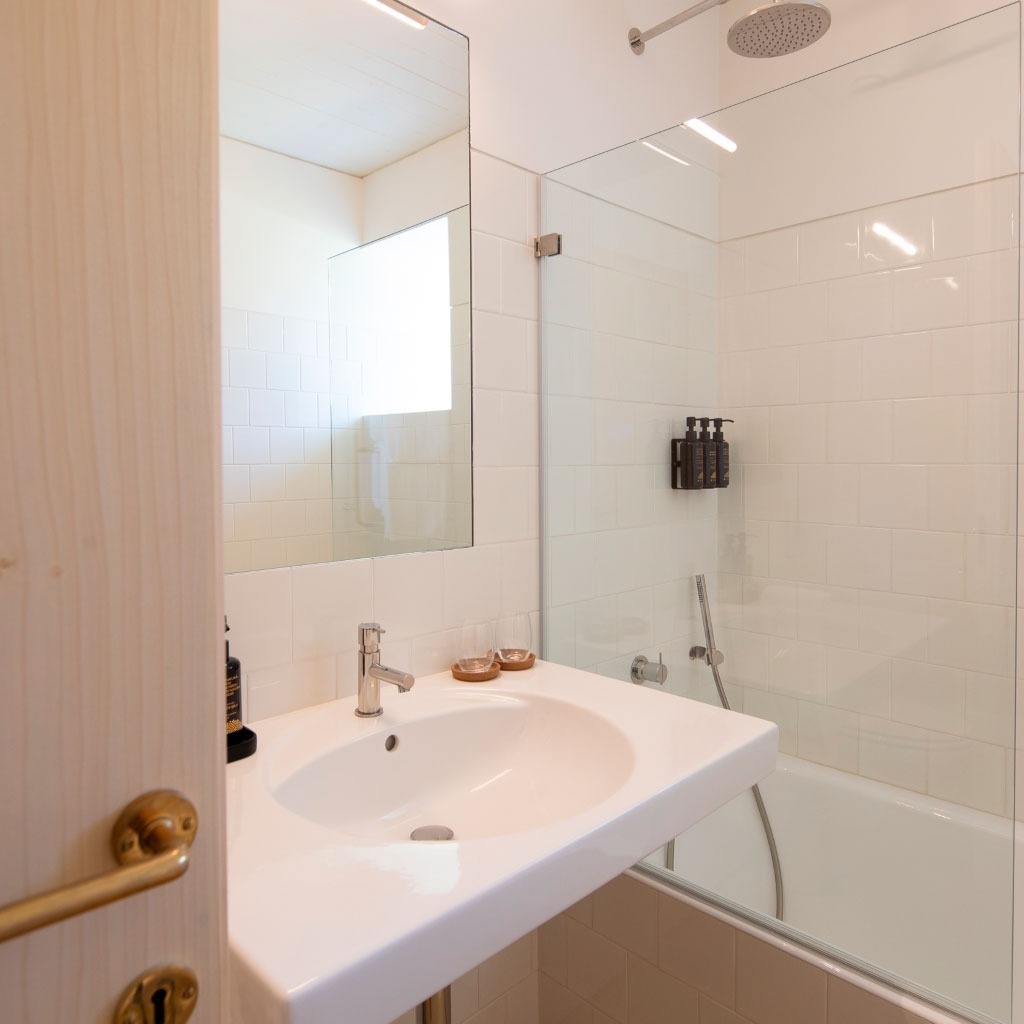 um banheiro com pia e chuveiro de vidro