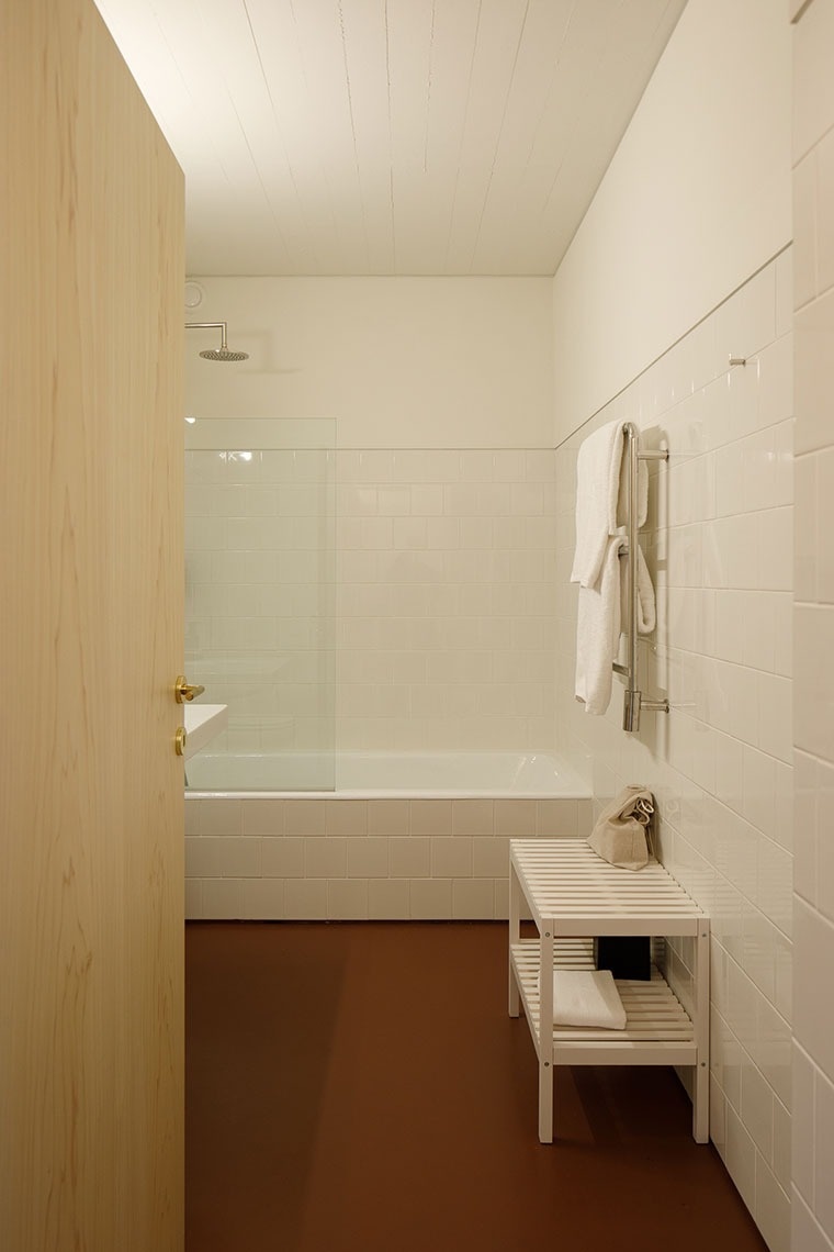 um banheiro com azulejos brancos e uma banheira