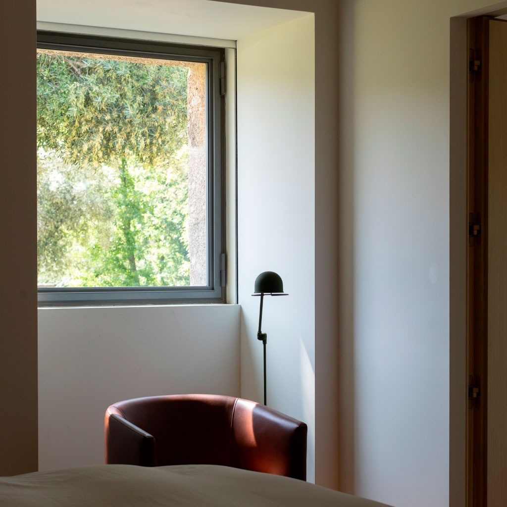 um quarto com uma cadeira e uma lâmpada ao lado de uma janela